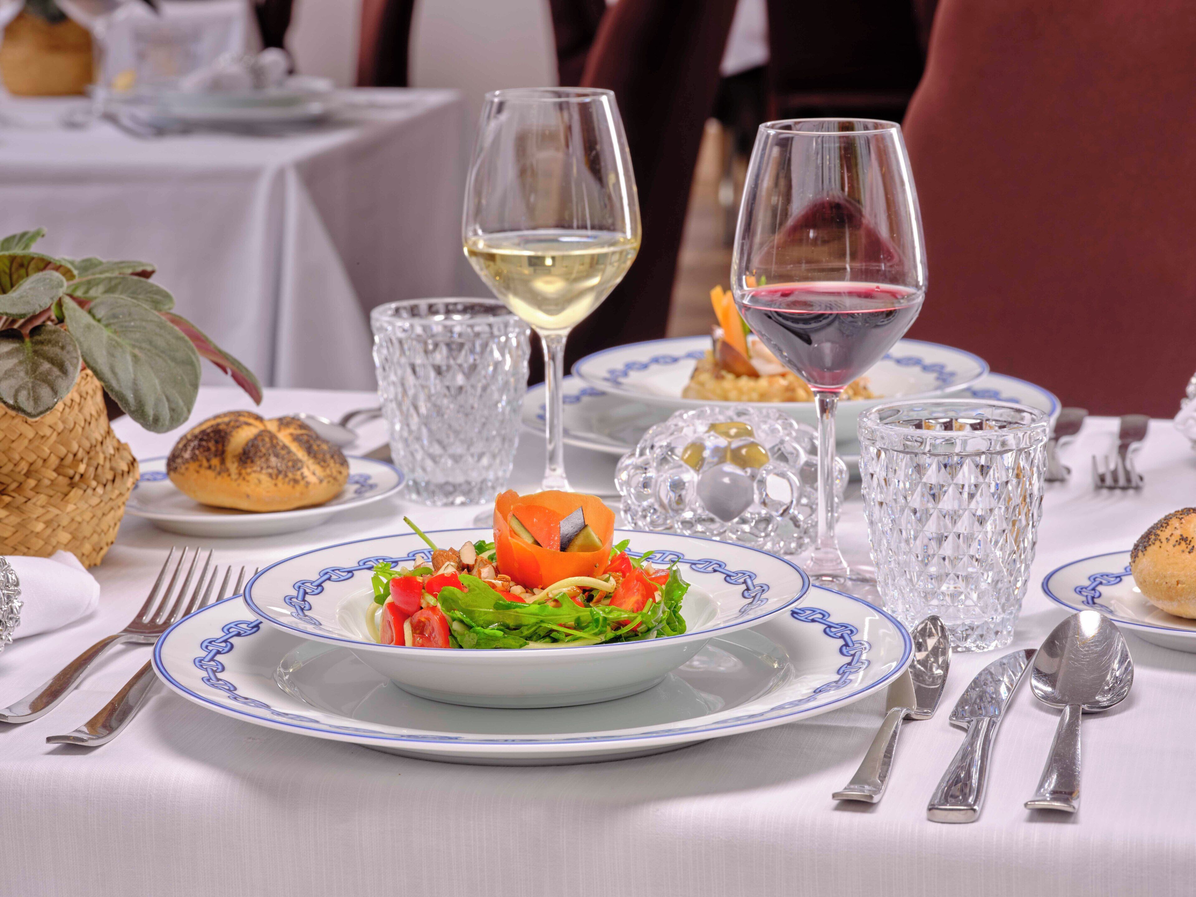 Un tavolo da pranzo imbandito con piatti di cibo, bicchieri di vino e posate.