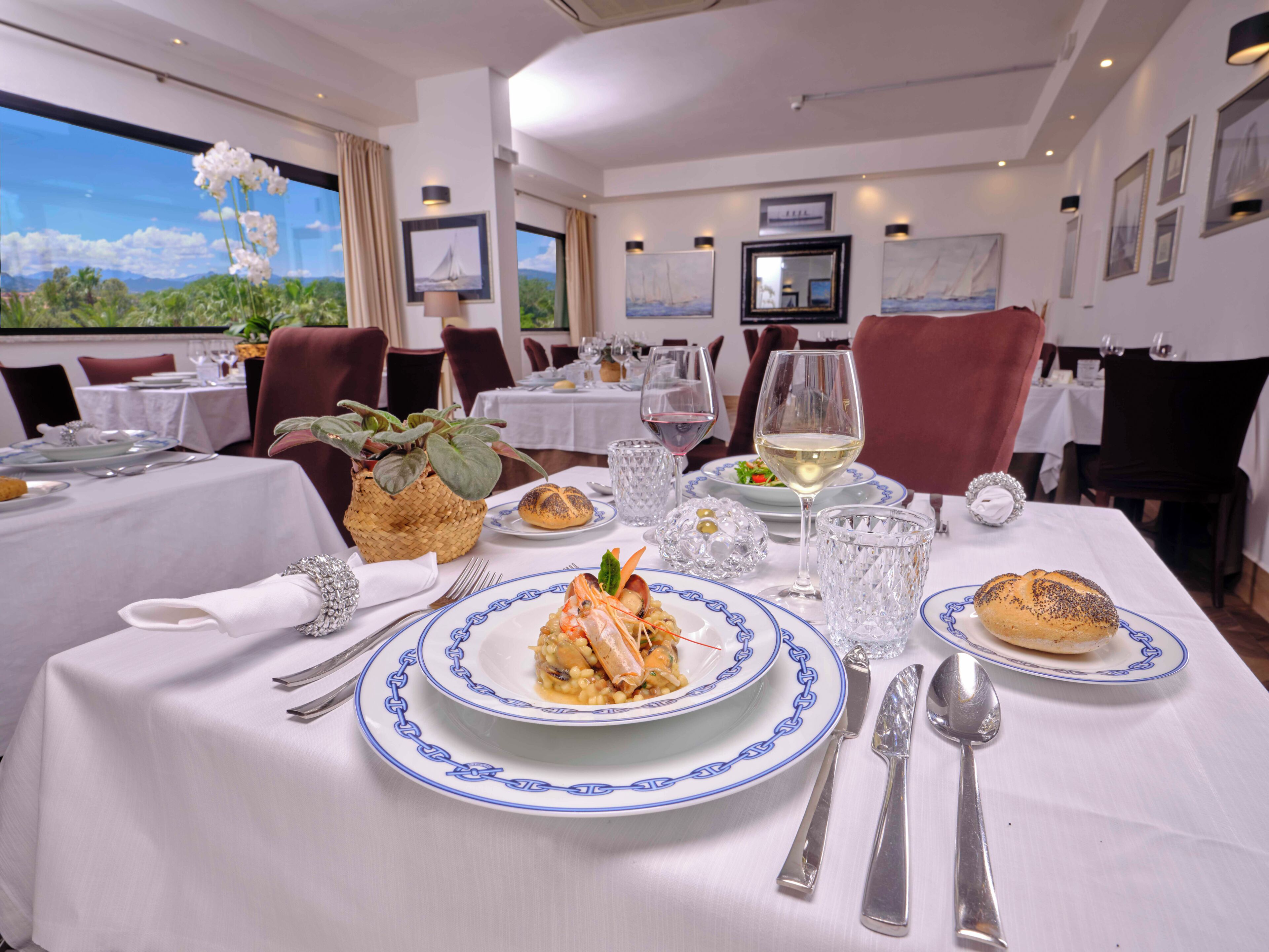 A dining area with tables set for meals, including plates with food and wine glasses.