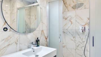 A bathroom with a white sink, a mirror, and a shower area.