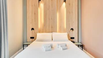 Een moderne hotelkamer met een groot bed, twee nachtkastjes en een houten hoofdbord met ingebouwde verlichting.