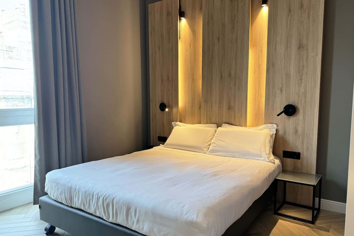 Ein modernes Schlafzimmer mit einem Bett, einer Holzwand und integrierter Beleuchtung.