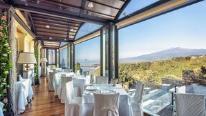 Un restaurante con mesas dispuestas para comer, amplias ventanas que ofrecen vistas a un paisaje montañoso.