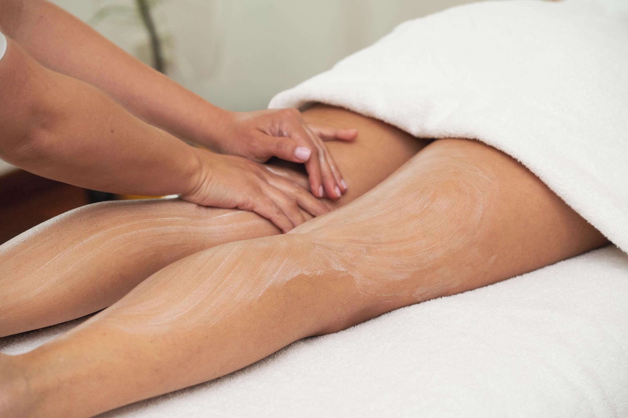 Iemand ontvangt een massage op een bed dat met een witte handdoek is afgedekt.