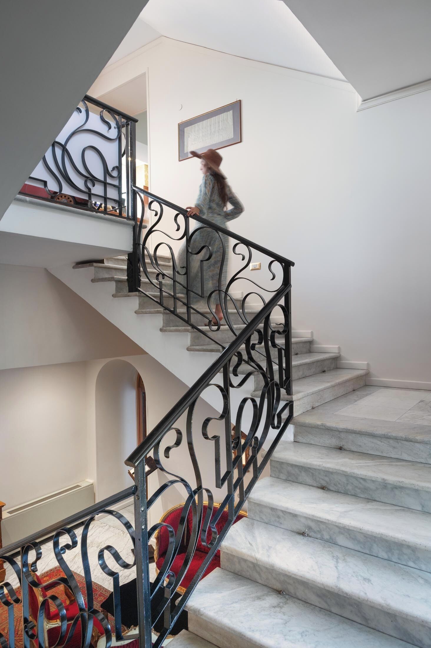 A staircase with a black wrought iron railing and marble steps.