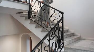 A staircase with a black wrought iron railing and marble steps.