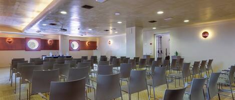 A conference room with rows of chairs, a podium, and a ceiling with recessed lighting.