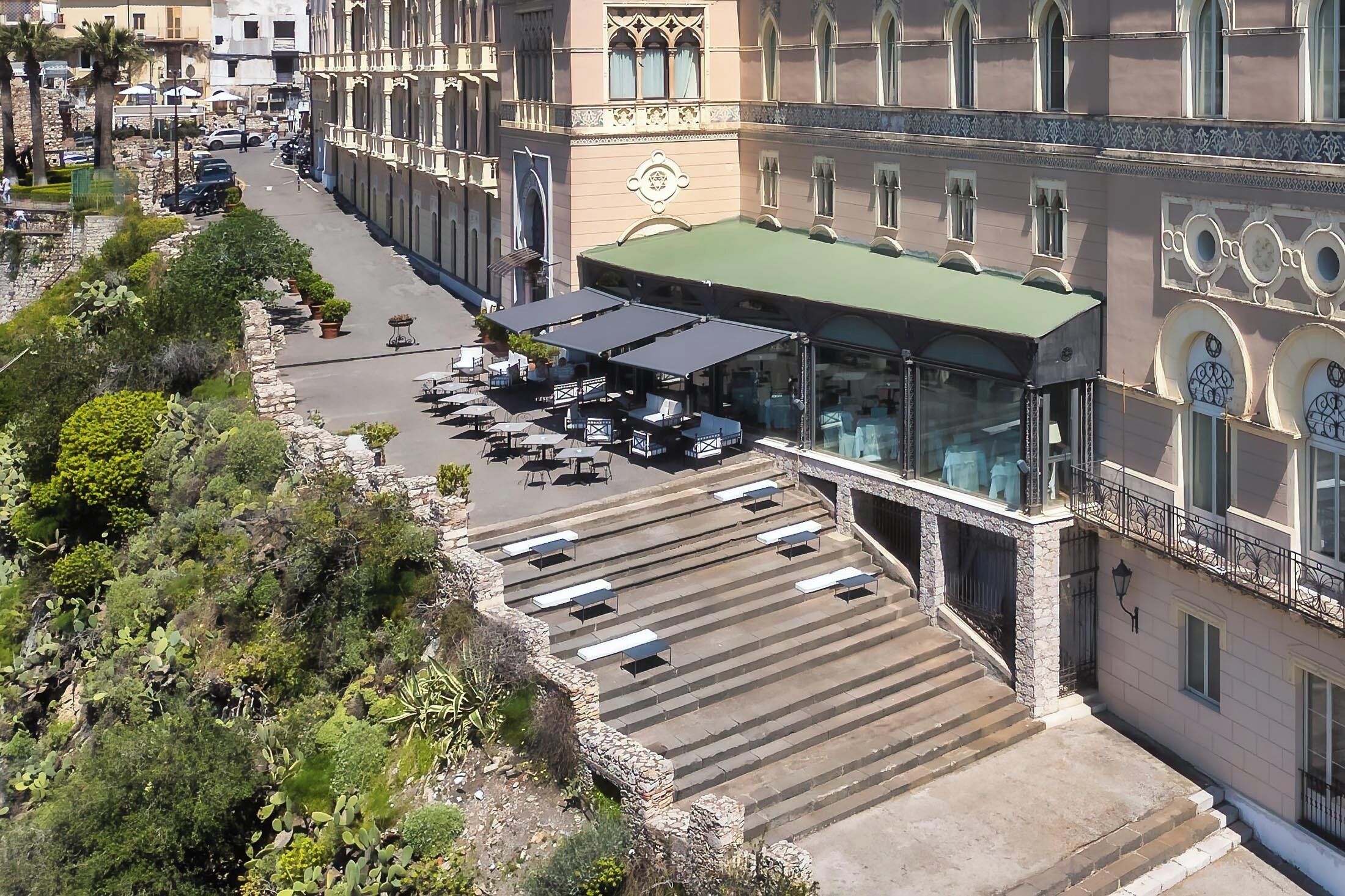A hotel with outdoor seating, a covered patio, and a staircase leading to the entrance.