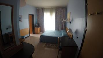 Ein Hotelzimmer mit Bett, Schreibtisch, Stuhl, Fernseher und einer Tür.