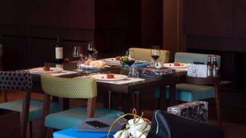 A dining area with a table set for two, featuring a bottle of wine, glasses, and a basket of flowers.