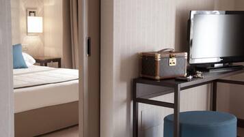 A hotel room with a bed, a television, a suitcase, and a small table.