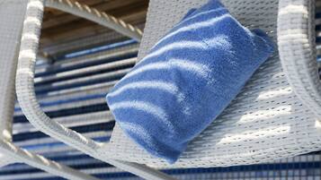 Una silla de mimbre blanca con una toalla azul sobre ella.