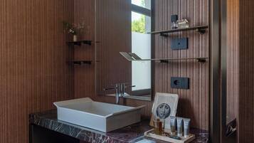 Ein modernes Badezimmer mit Marmorplatte, einem großen Spiegel und einer eingebauten Ablage mit Toilettenartikeln.
