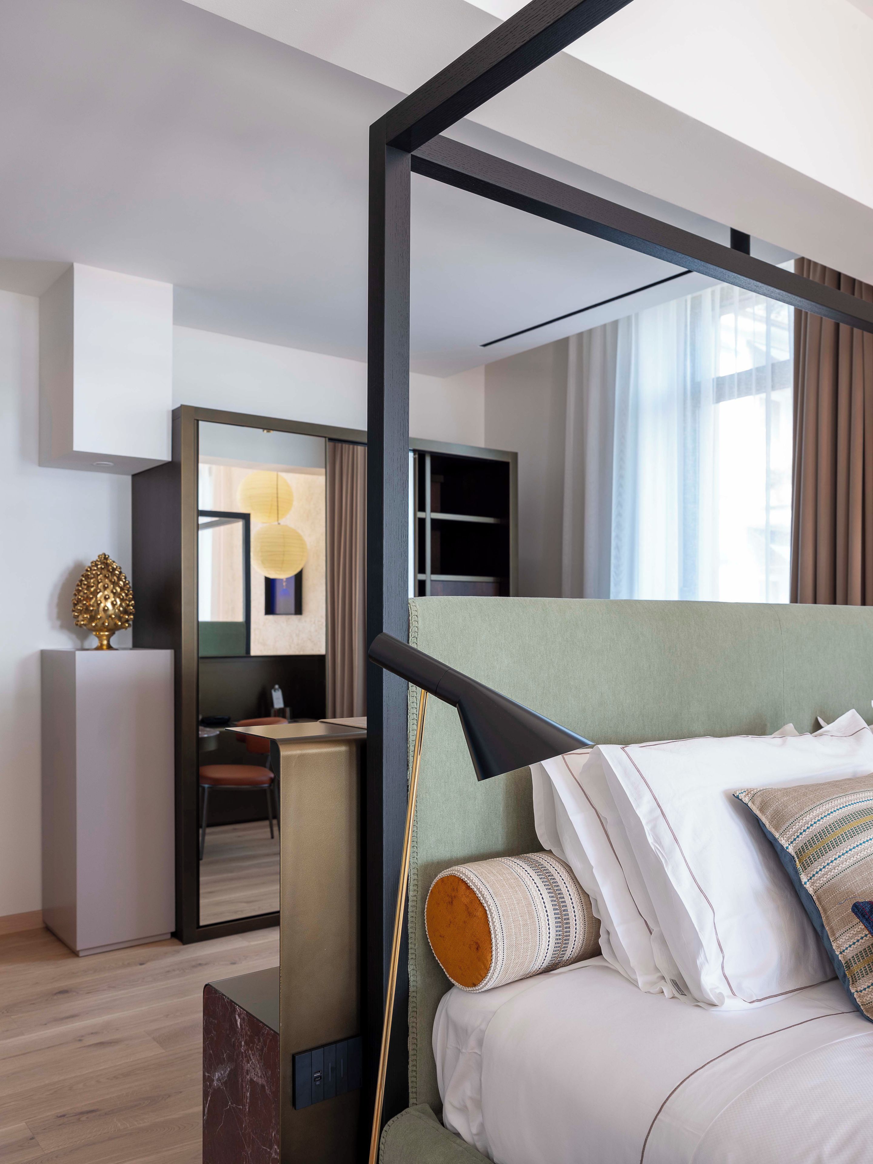 Ein modernes Hotelzimmer mit Bett, Schreibtisch, Spiegel und Blick ins Freie.