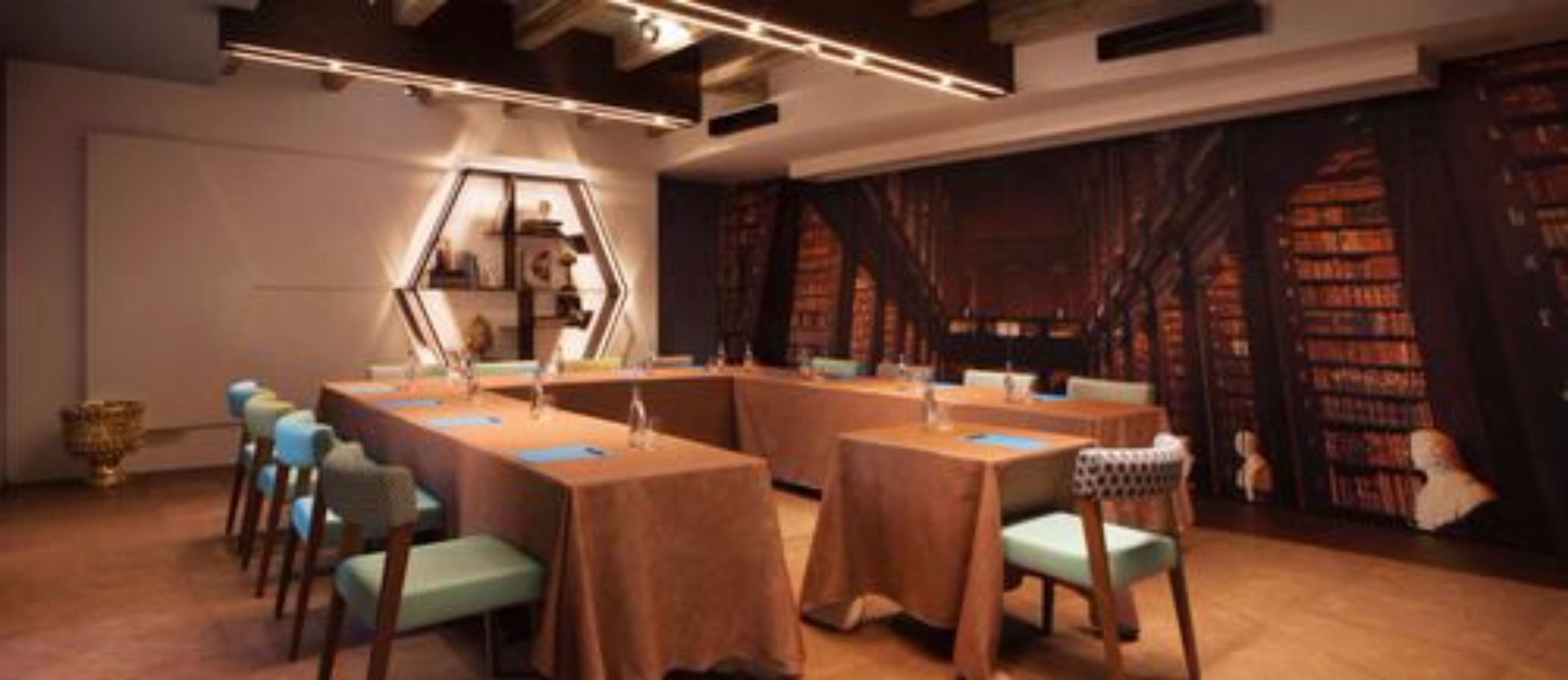 A conference room with a long table and chairs, a hexagonal display, and bookshelves in the background.
