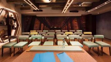 Un salón de conferencias con filas de sillas, un atril y una pantalla grande.