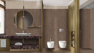 A modern bathroom with a marble vanity, a round mirror, a toilet, and a wall-mounted shelf with toiletries.