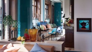 Un moderno vestíbulo de hotel con zona de estar, ventanas amplias y una obra de arte colgada en la pared.