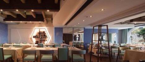 A modern restaurant interior with hexagonal light fixtures, wooden ceiling beams, and a mix of table and booth seating.