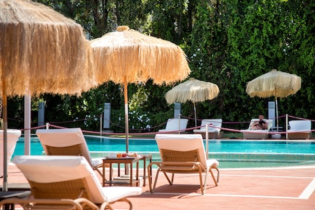 Una piscina al aire libre de temporada, sombrillas
