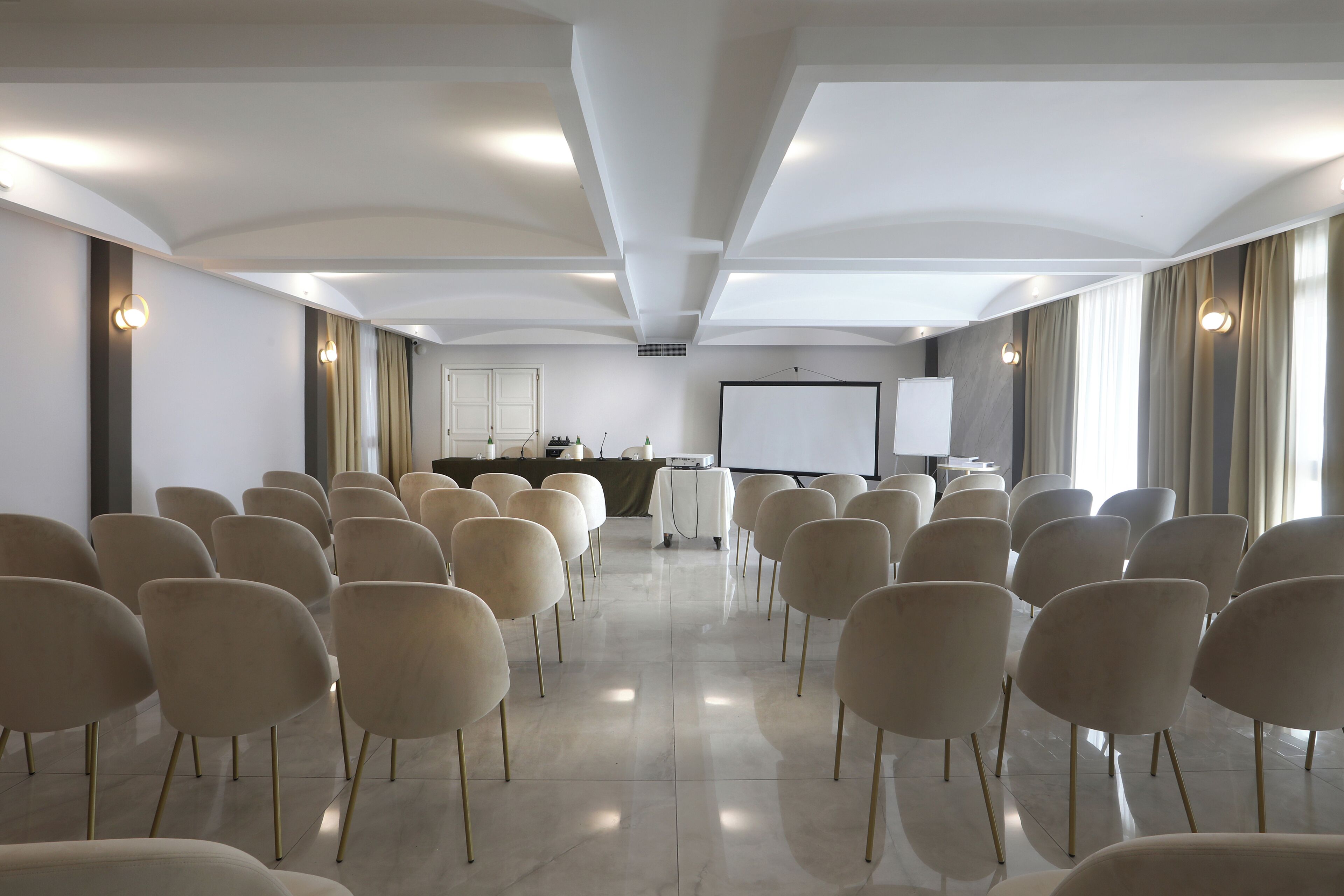 A conference room with rows of chairs, a projector screen, and a presentation area.