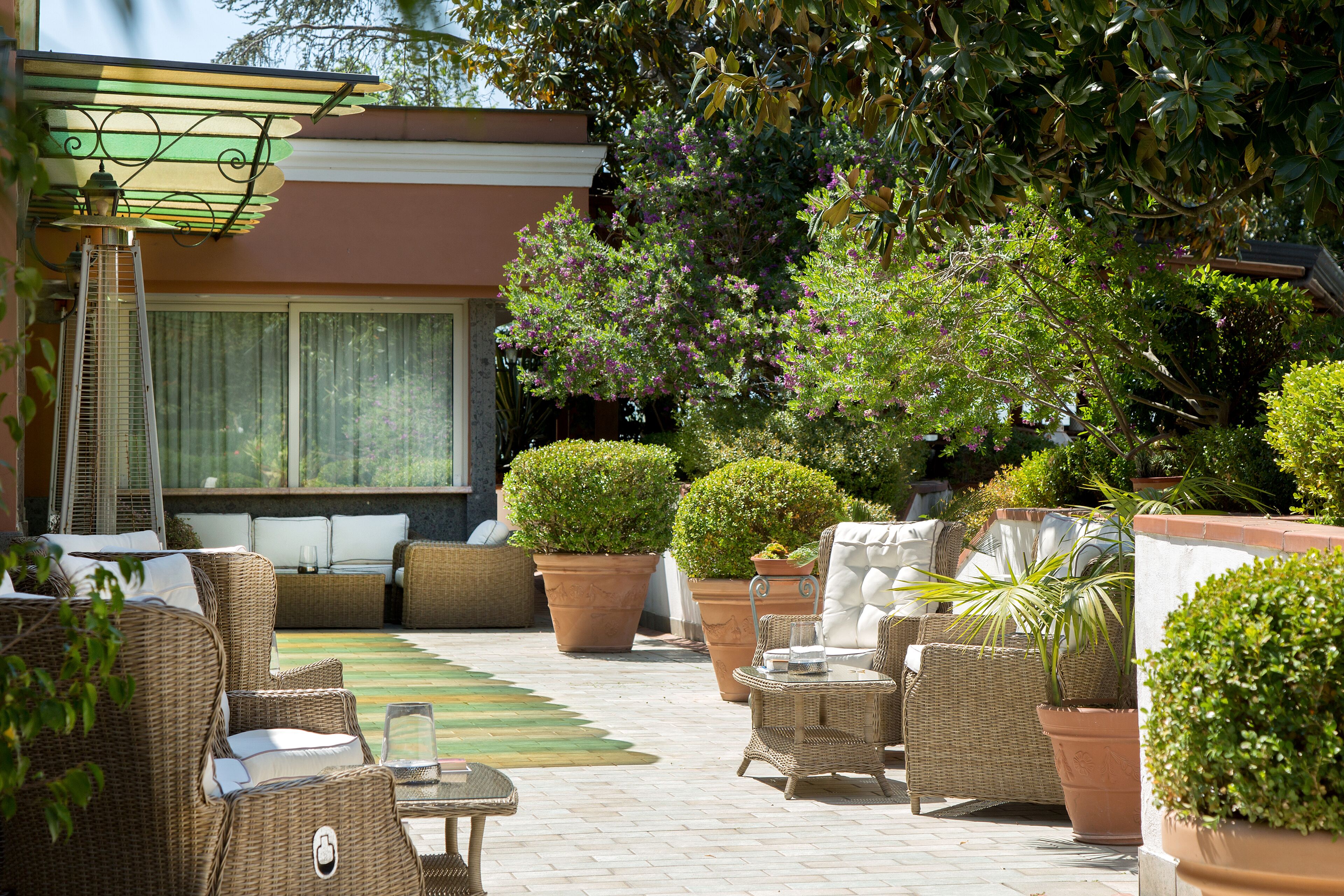 A patio area with wicker furniture, potted plants, and a pergola.