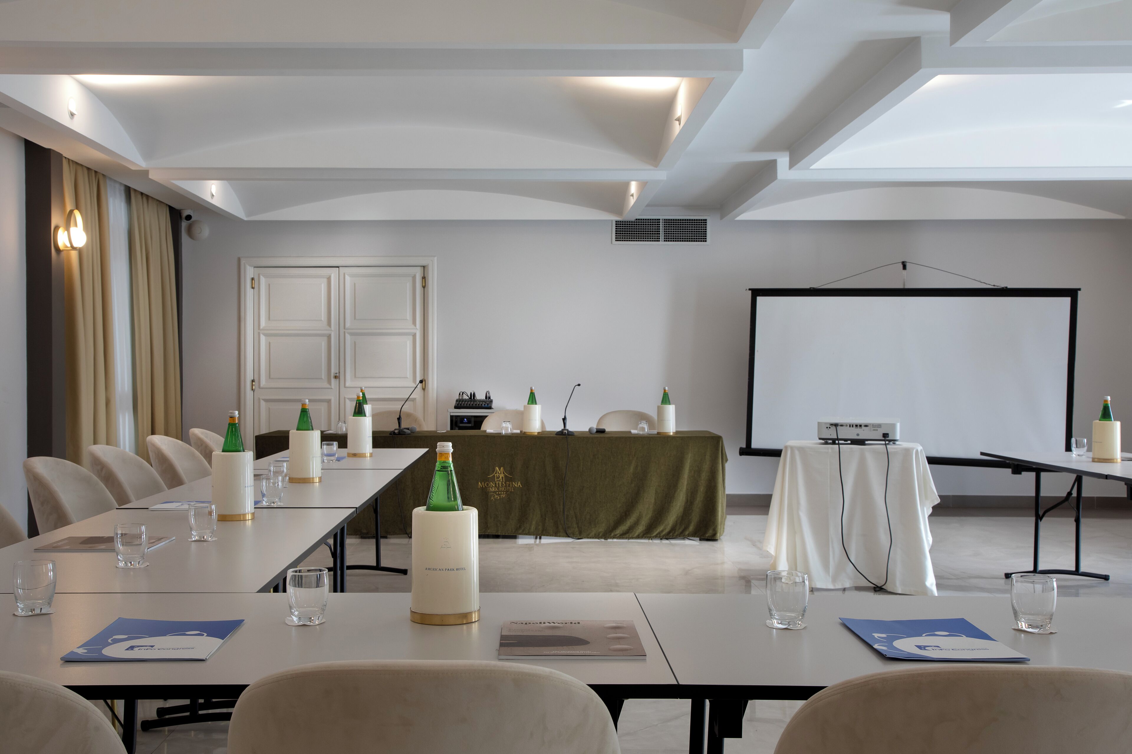 A conference room with a long table, chairs, a projector screen, and a whiteboard.