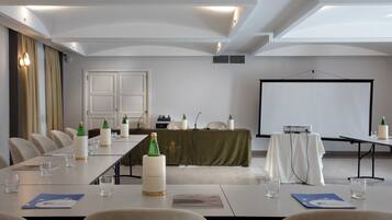 A conference room with a long table, chairs, a projector screen, and a whiteboard.