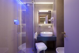 Un bagno moderno con cabina doccia in vetro, lavabo rotondo e specchio grande.
