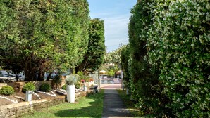 A pathway flanked by neatly trimmed hedges and a brick wall with a small garden area. - Montespina Park Hotel (Naples)