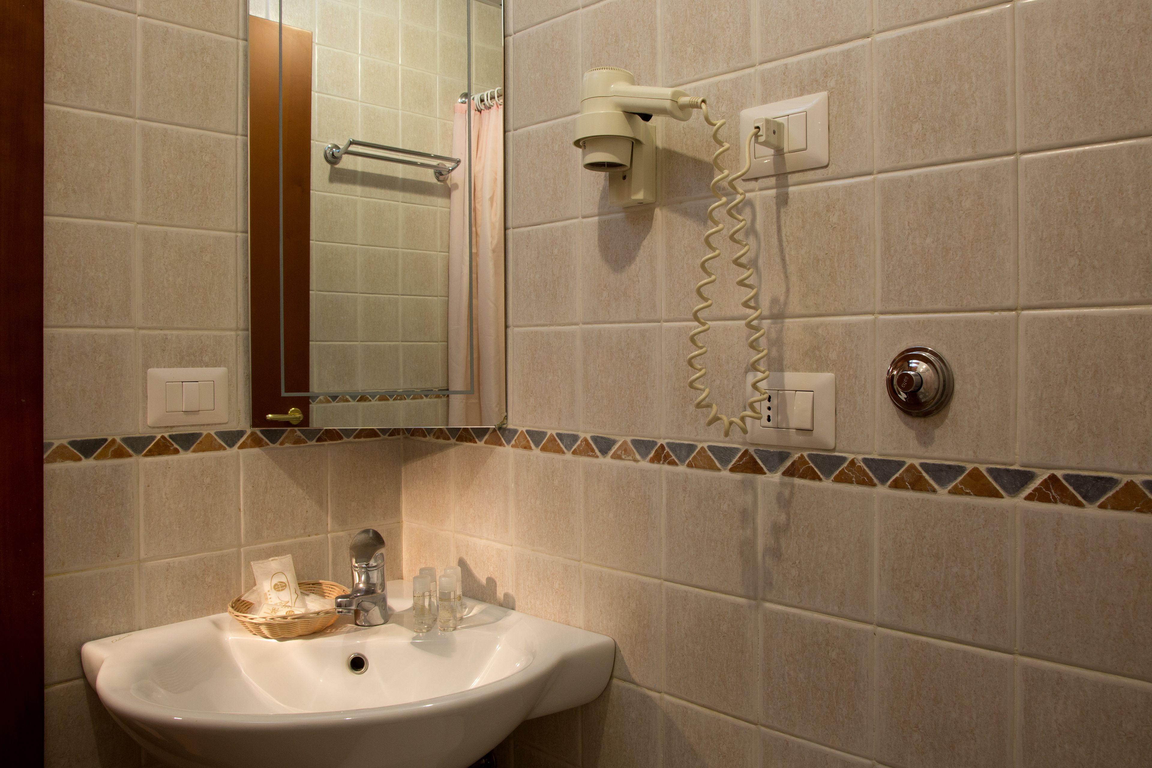 A bathroom with a sink, mirror, towel rack, and hairdryer.