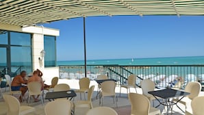 Una terrassa amb seients a l'exterior i vista a la platja.
