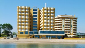Hotel de diverses plantes amb balcons, situat a prop d'una platja d'aigua cristal·lina.