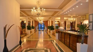 Rebedor d'hotel amb una gran pèndol, una taula de recepció i un ampli emblema al sòl.
