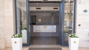 The entrance to HOTEL DE PLAM with a reception desk, a tiled floor, and two potted plants. - De Plam (Olbia)