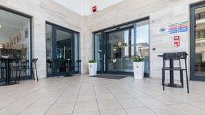 A hotel entrance with a reception desk, two chairs, and a potted plant. - De Plam (Olbia)