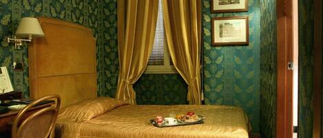 Une chambre avec un lit, un bureau doté d’une lampe et un plateau contenant des articles pour le petit-déjeuner.