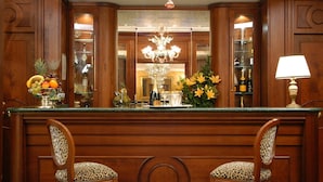 A bar area with a mirror, two leopard-print chairs, a fruit bowl, a chandelier, and a lamp. - LH Hotel Andreotti (Rome)