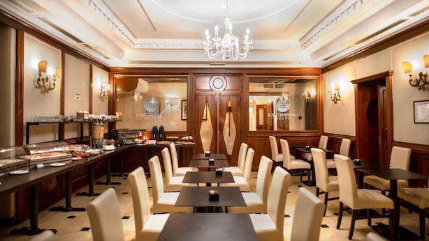 A hotel dining area with a long buffet table, multiple dining tables, and chairs. - LH Hotel Andreotti (Rome)