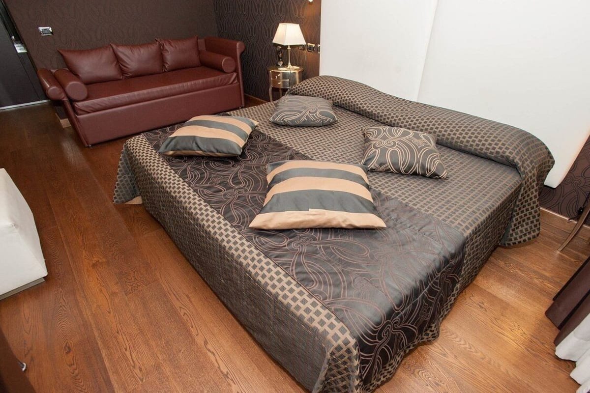 Une chambre avec un grand lit, un canapé rouge et une petite table avec une lampe.