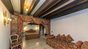 A room with a bed, a sofa, a chair, and a small table. There is a brick wall and a wooden ceiling. - Pantalon Hotel (Venice)