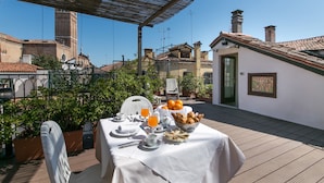 A rooftop terrace with a table set for breakfast, including croissants, fruit, and orange juice. - Pantalon Hotel (Venice)