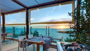 A dining area with a view of the sea at sunset, featuring a table set for two with a bottle of champagne. - Smy Carlos V Alghero (Alghero)