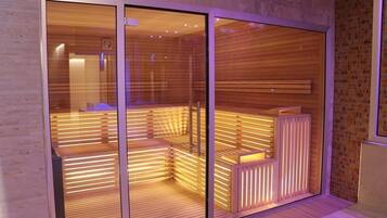 A sauna with wooden slats and glass doors, featuring a bench and a small table.