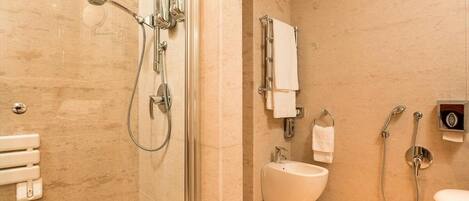 A modern bathroom with a glass-enclosed shower, a bidet, and a toilet.