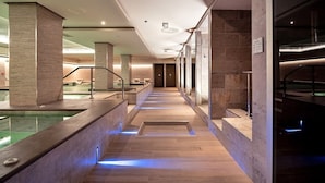 A modern indoor pool area with a long, narrow pool, wooden flooring, and glass walls. - Smy Carlos V Alghero (Alghero)