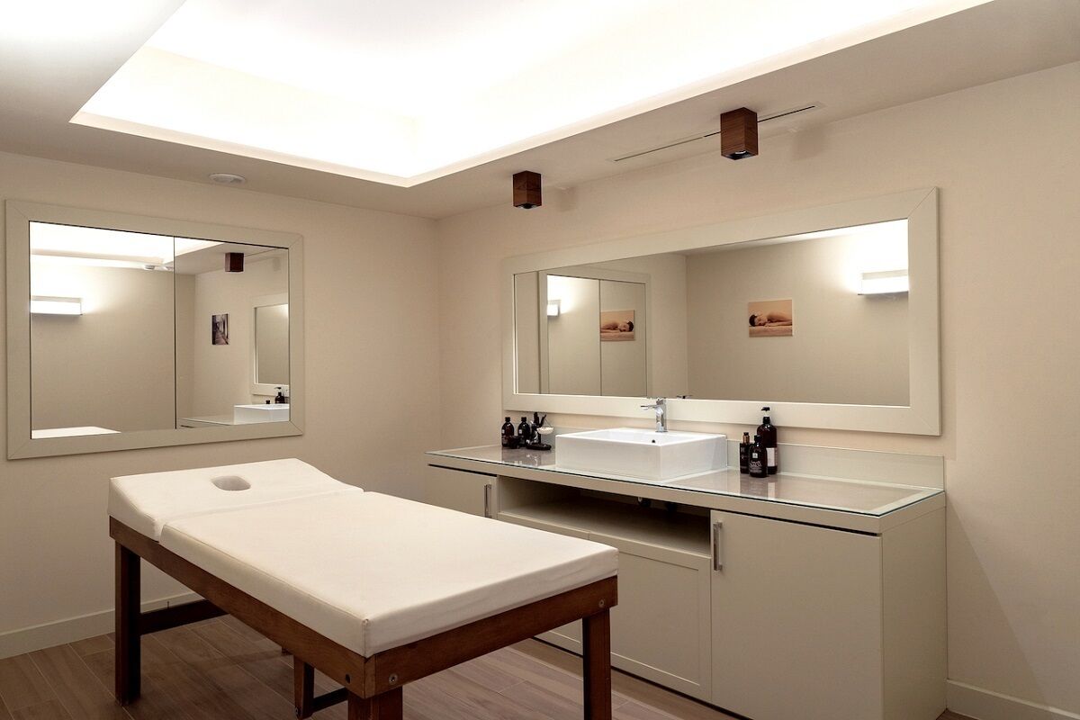 Un baño moderno con un espejo grande, un lavamanos blanco y un banco de madera.