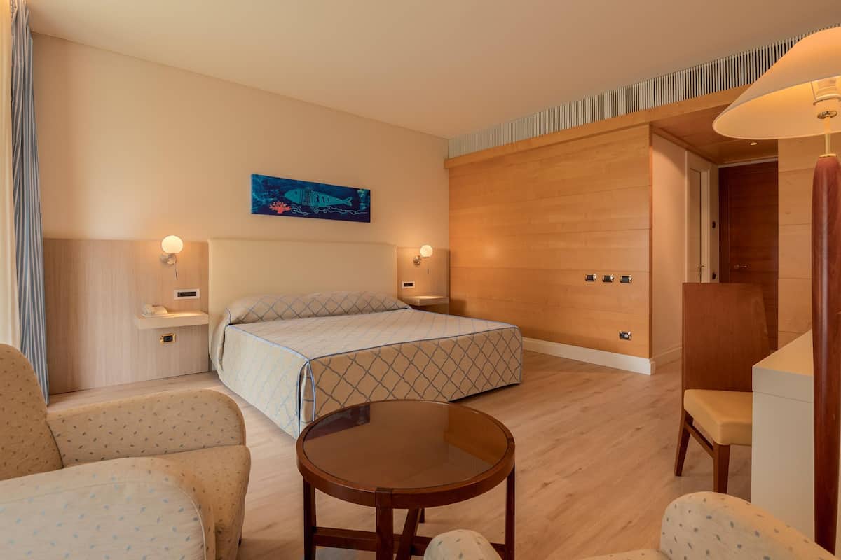 A hotel room with a bed, two bedside tables, a round table, and a chair.
