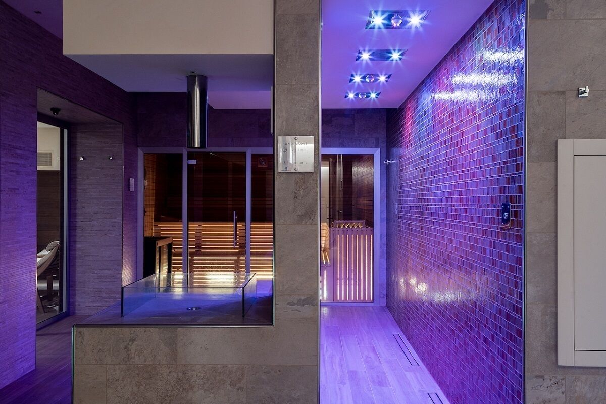 Ein modernes Interieur mit einer Glaskabine, einer Fliesenwand und einer Decke mit eingelassener Beleuchtung.