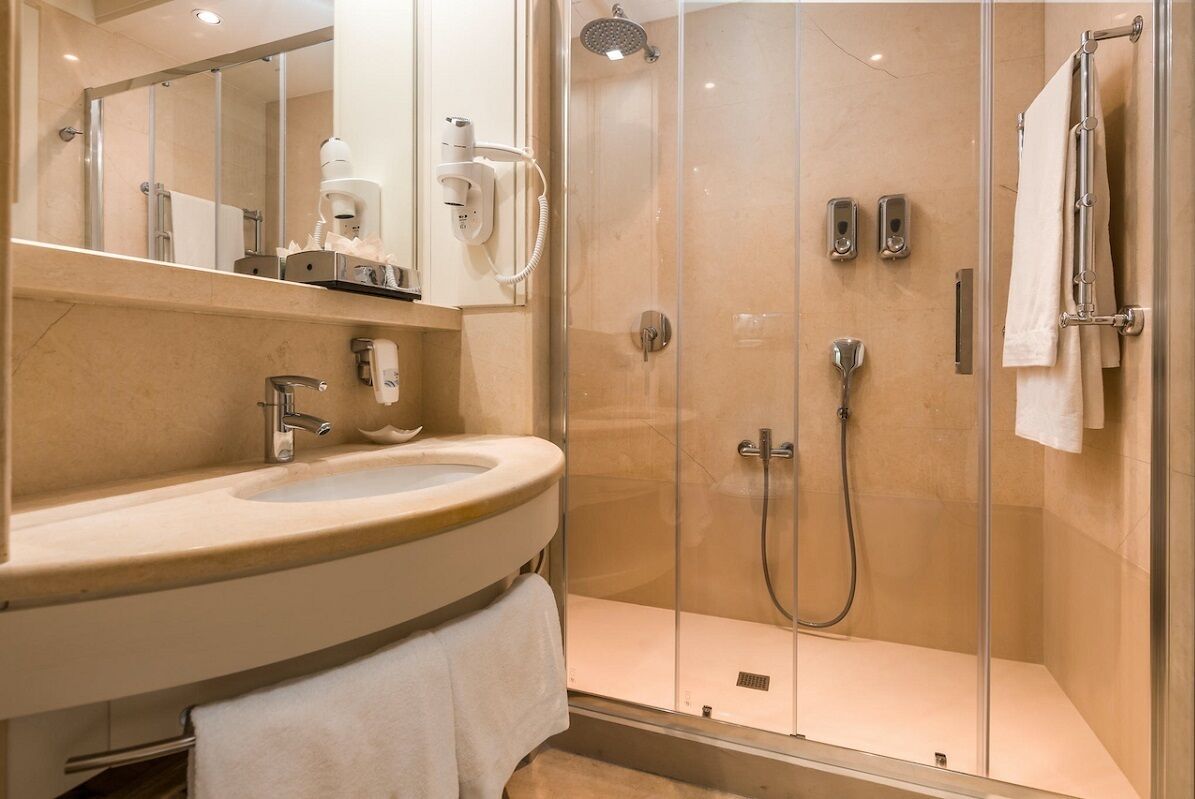 A modern bathroom with a curved sink, a glass-enclosed shower, and a mirror above the sink.