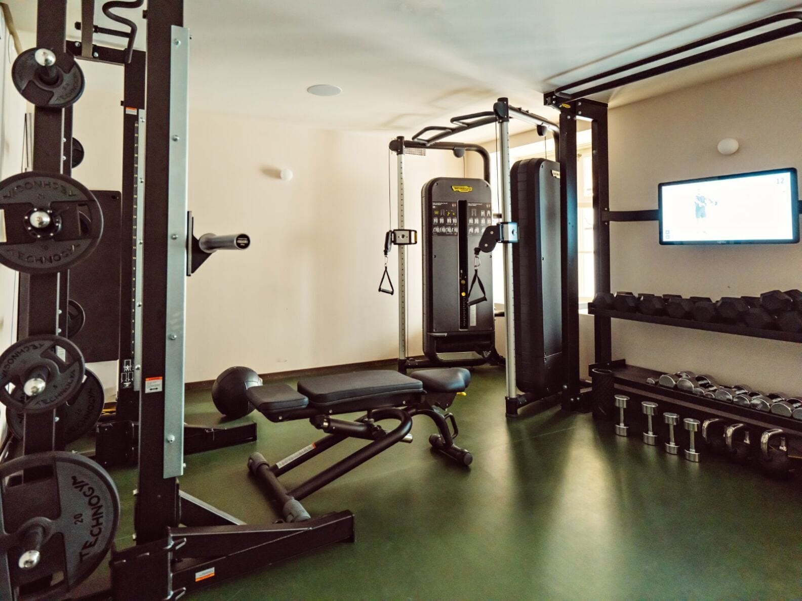 Une salle de sport équipée de matériel de musculation, d’un banc et d’haltères.